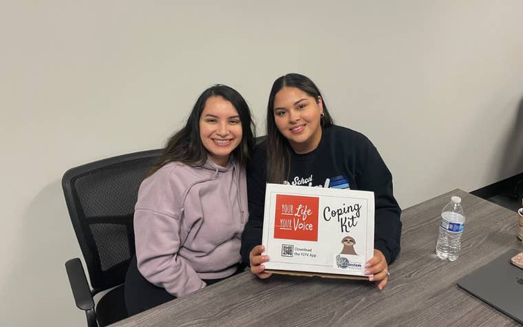 Two women smiling holding up a sign 